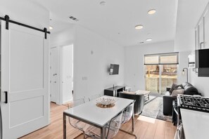 Et moderne køkken med spiseplads, en sofa og et fjernsyn ophængt på væggen.