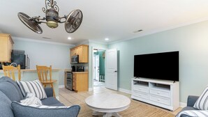 A living room with a grey sofa, a round coffee table, and a flat-screen TV. - NEW Surfside Beach 2 BR 1 BA Unit with Hot Tub minutes to private beach access (Murrells Inlet)