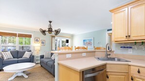 A compact kitchen with a dishwasher, a sink, and wooden cabinets. There is a dining area with a round table and two sofas. - NEW Surfside Beach 2 BR 1 BA Unit with Hot Tub minutes to private beach access (Murrells Inlet)