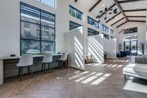 Un interior espacioso y luminoso con ventanas amplias, suelo de madera en patrón de espiga y mobiliario moderno.