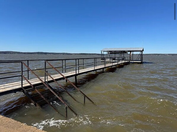Un muelle que se adentra en una masa de agua con una estructura cubierta al final.
