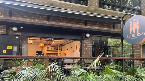 A coffee bar named 'Tres Helenas' with a brick facade, indoor seating, and potted plants. - Be Together By Roots Rentals (Medellín)