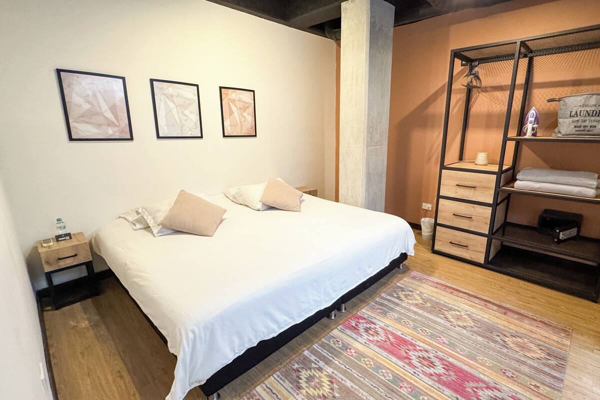A neatly arranged bedroom with a bed, bedside tables, a wardrobe, and a rug.