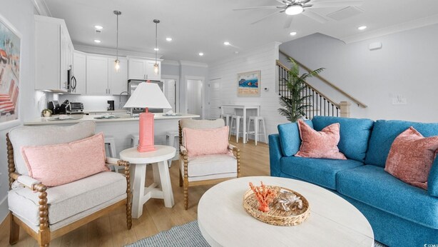 A modern living room with a blue sofa, a round coffee table, and a kitchen in the background. - Spacious 4 Bedroom 3.5 Bathroom walking distance to the beach. Close proximity! (Myrtle Beach)