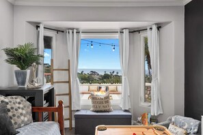 Ein Balkon mit Blick auf den Ozean, ein Holzstuhl, ein kleiner Tisch und ein Topfpflanze.