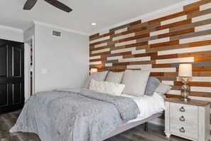 Ein Schlafzimmer mit Bett, Nachttisch und einer Wand mit Holzpaneelen.