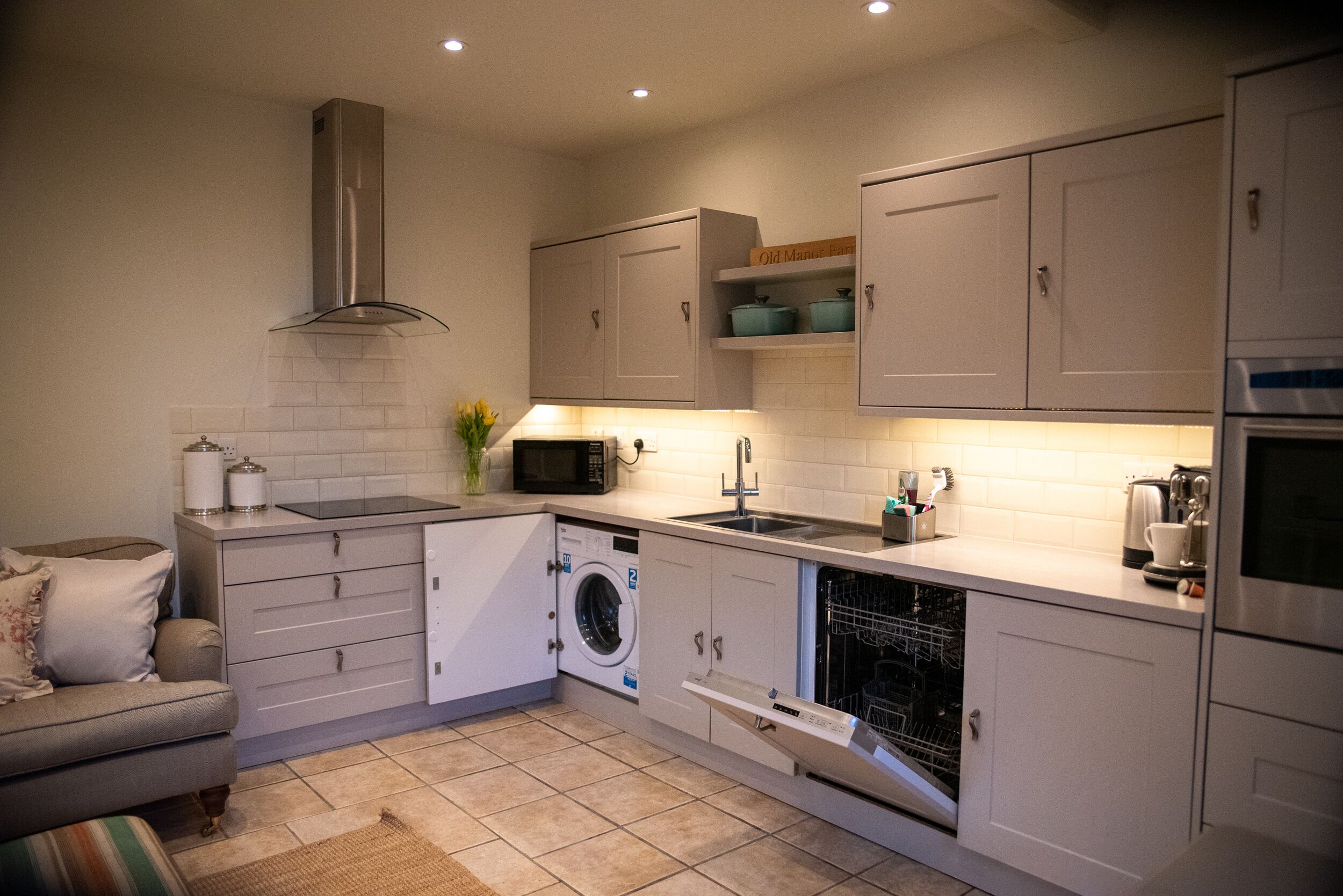 A compact kitchen with a washing machine, microwave, and dishwasher.