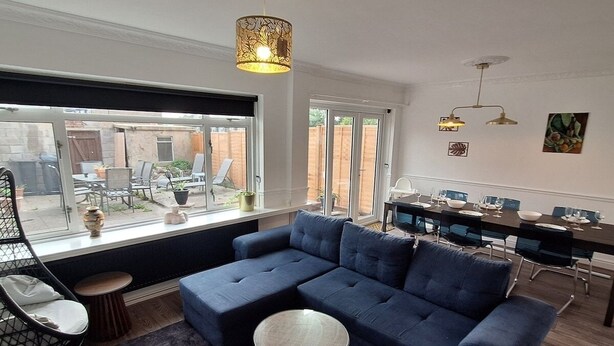 A modern living room with a sectional sofa, a round coffee table, and a dining area with a long table and chairs.