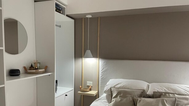 Un dormitorio con cama, mesita de noche, espejo y armario.