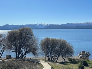 A lakeside view with mountains in the background, a clear sky, and a pathway leading to the water.