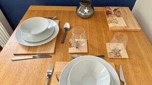 A wooden dining table set with plates, cutlery, glasses, and a decorative candle holder.