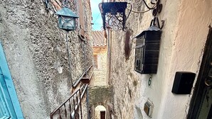 Uma escadaria de pedra estreita que leva a um andar superior em um edifício histórico, com uma porta azul e grades de metal.