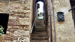 Uma escadaria de pedra histórica leva a uma porta em arco, com um quadro de correio e caixas elétricas nas paredes.