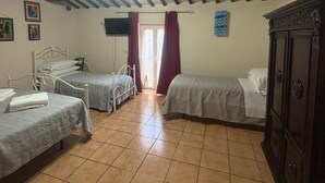 Quarto com duas camas de solteiro, guarda-roupa de madeira, televisão de ecrã plano e janela com cortinas.