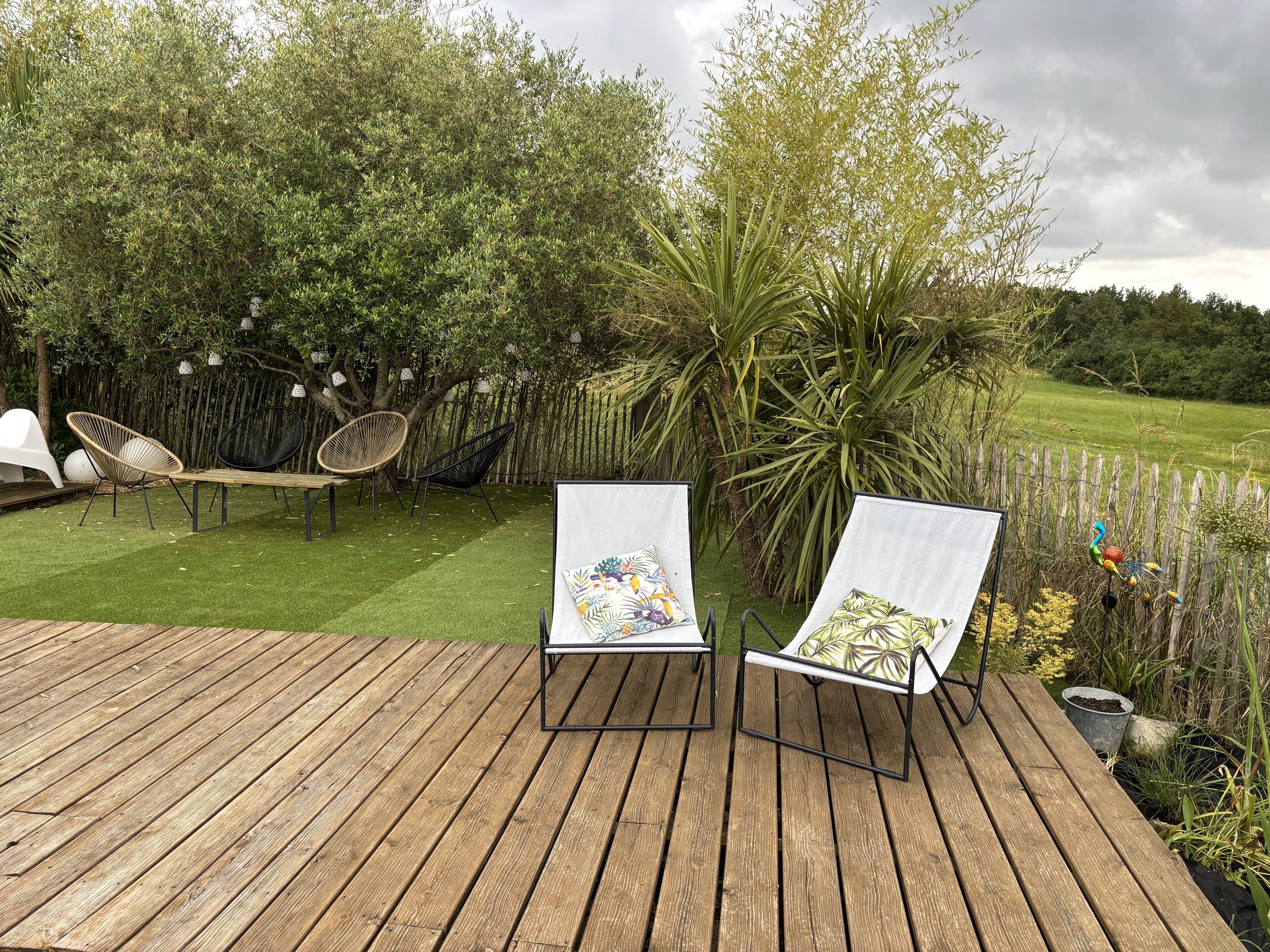 A wooden deck with two lounge chairs, a hammock, and a small table.