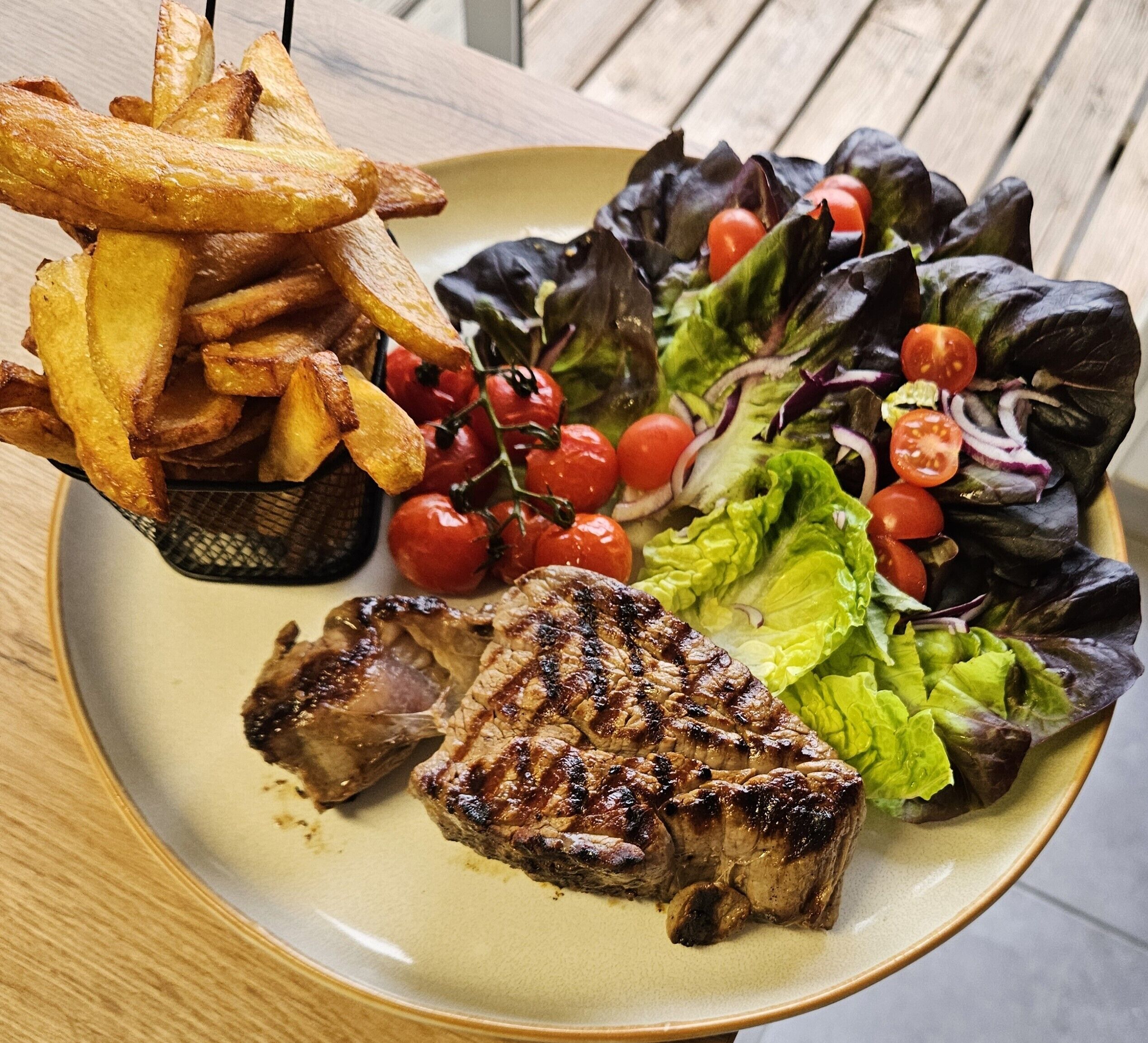 A plate with grilled meat, a side of fries, and a salad.