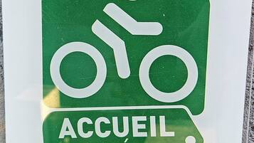 A green welcome sign with a bicycle symbol and the words 'ACCUEL VÉLO' and 'BIENVENUE WELCOME' on a white background.