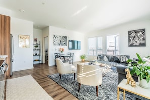 A modern living room with a sofa, a coffee table, and a dining area with chairs and a table.