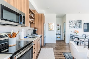 A modern kitchen with wooden cabinets, stainless steel appliances, and a dining area with a table and chairs.