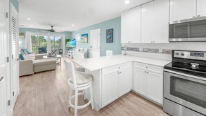A modern kitchen with white cabinets, stainless steel appliances, and a large island.