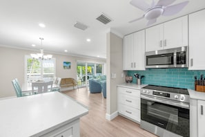 A modern kitchen with white cabinets, a stainless steel microwave, and an oven.