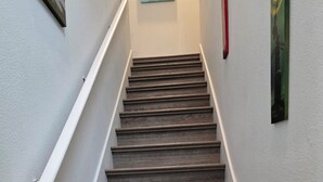 A staircase with wooden steps and white handrails, leading to a landing with a painting. - 2B/2B College Park home w/fenced patio yard, close to DT Orl & WP. Pet Friendly! (Orlando)