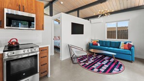 A modern kitchen with a built-in microwave and oven, a blue sofa with colorful cushions, and a round rug. - Bright, Modern 1BR ADU in Claremont with Seamless Indoor-Outdoor Living (Claremont)