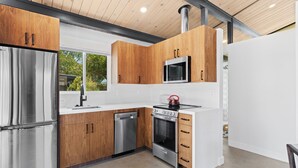A modern kitchen with stainless steel appliances, wooden cabinets, and a white countertop. - Bright, Modern 1BR ADU in Claremont with Seamless Indoor-Outdoor Living (Claremont)