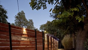 A wooden fence with lights, a pathway, and flowering plants. - Bright, Modern 1BR ADU in Claremont with Seamless Indoor-Outdoor Living (Claremont)