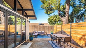 A backyard with a wooden fence, a patio with a table and chairs, and a built-in seating area with cushions. - Bright, Modern 1BR ADU in Claremont with Seamless Indoor-Outdoor Living (Claremont)