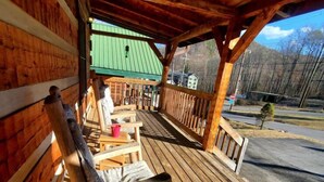 Eine Holzterrasse mit Schaukelstuhl, Tisch und Bank.