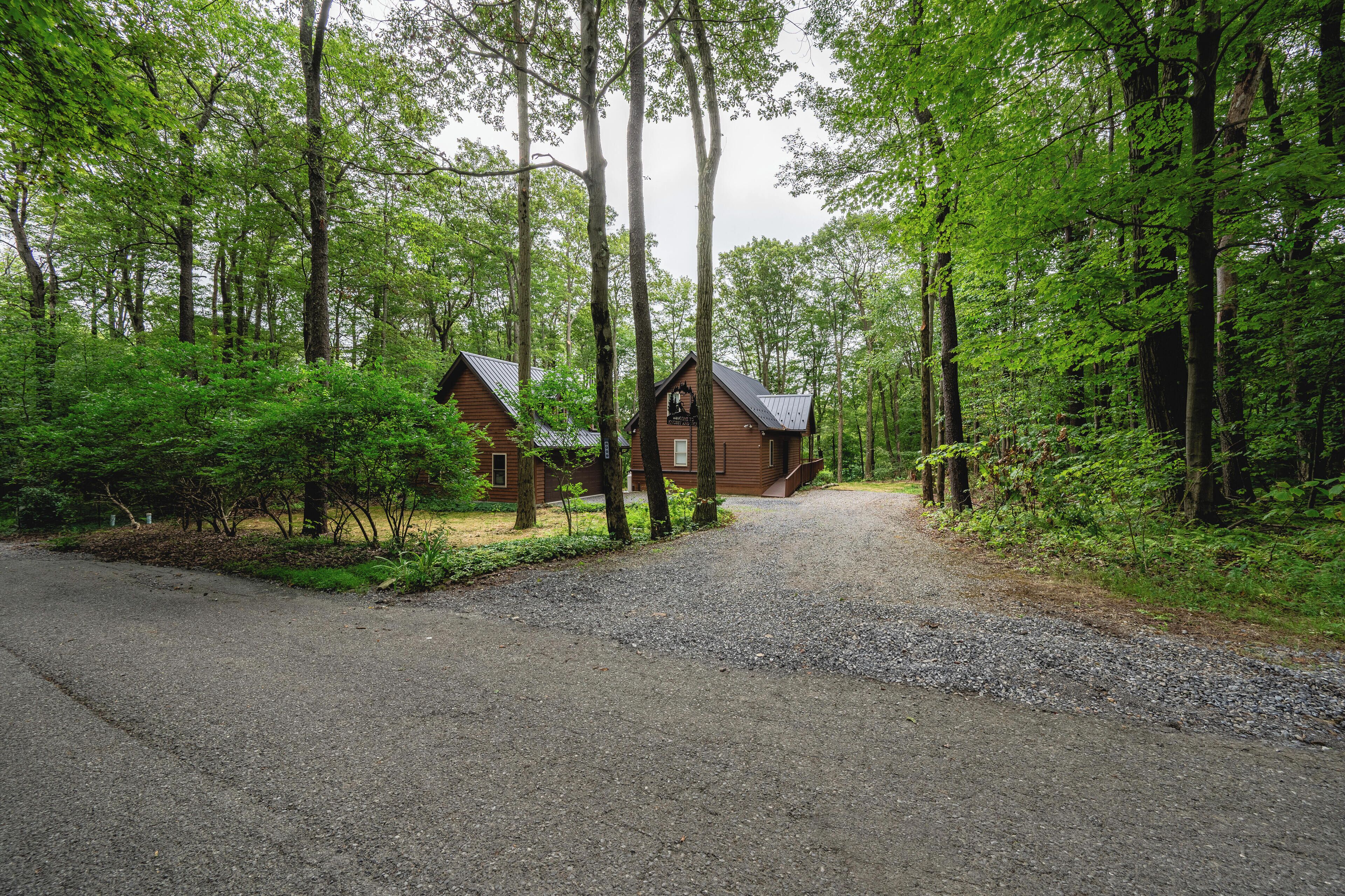 Eine Hütte, umgeben von dichtem Wald, mit einem Schotterweg, der dorthin führt.