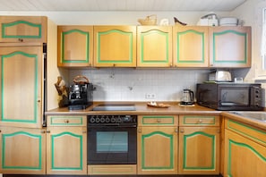 Une cuisine avec des meubles de rangement en bois, une cuisinière, un four à micro-ondes et une machine à café.
