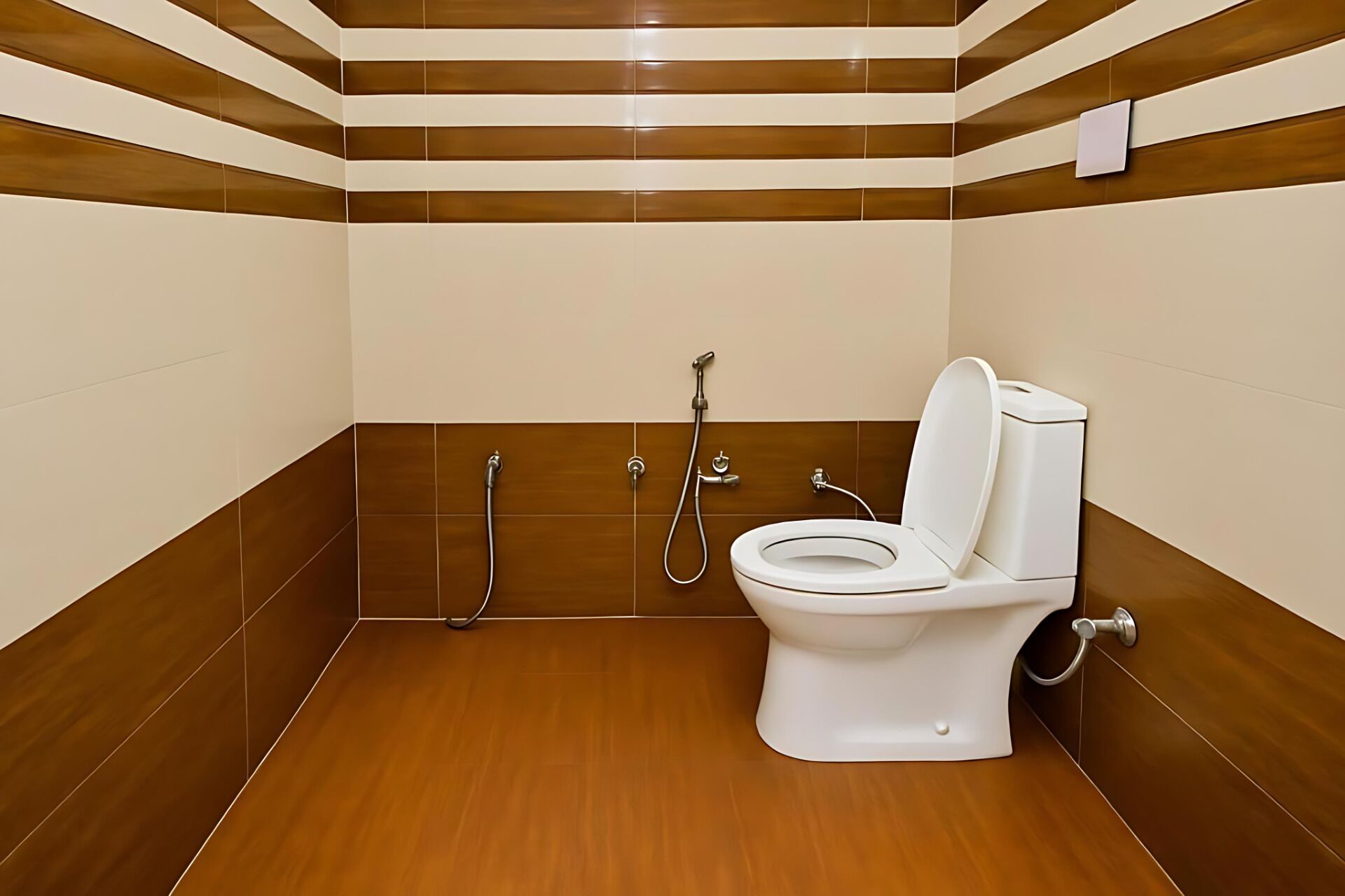 A bathroom with a toilet, a shower, and a bidet. The walls are tiled with a brown and beige pattern.