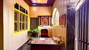 A hallway with a reception desk, a potted plant, and a framed picture on the wall. - hotel shraddha palace (Faizabad)