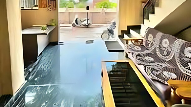 A modern interior with a central glass table, a sofa with patterned cushions, and a staircase leading to an outdoor area. - hotel shraddha palace (Faizabad)