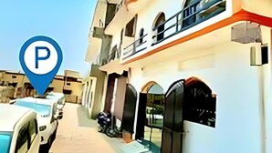 A multi-story building with a parking area in front. - hotel shraddha palace (Faizabad)