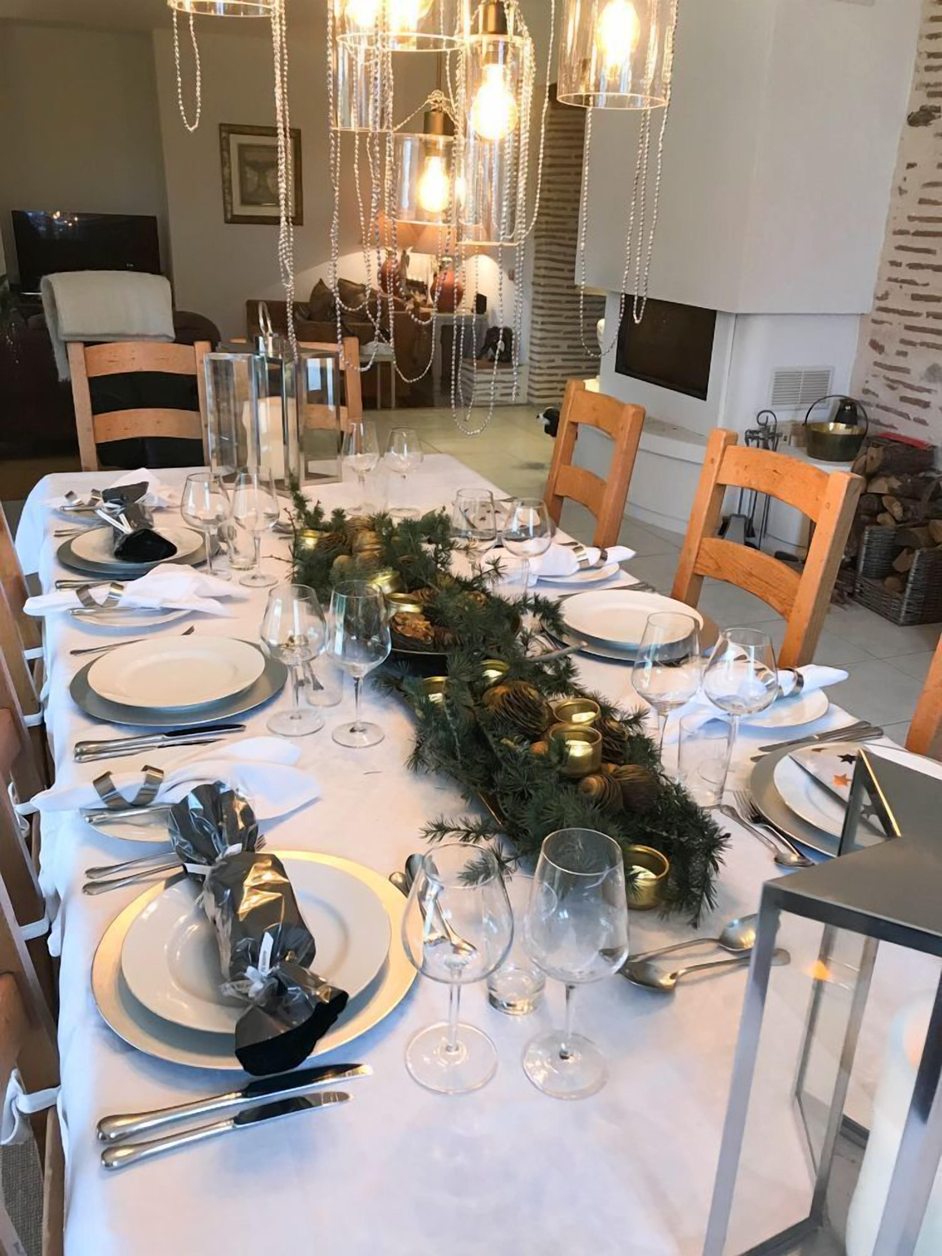 A dining area with a long table set for a meal, featuring clear glassware, plates, and cutlery.
