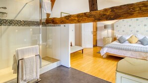 A bedroom with a bed, bedside table, and a nightstand. There is a glass shower enclosure with a towel rack. The room has wooden beams on the ceiling and a tiled shower area. - Manoir Des Cedres - Eight Bedroom Castle, Sleeps 20 (Castelmoron-sur-Lot)