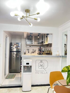 A compact kitchen with a refrigerator, a water dispenser, and a countertop with kitchen utensils. - RQ Pool Villa, Angeles City (Angeles City)