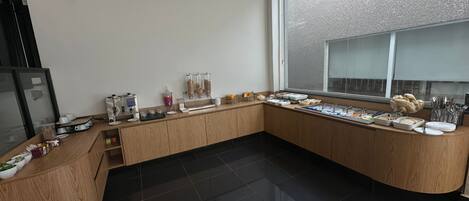 A modern kitchen with a curved wooden countertop, a coffee machine, and various food items displayed on the counter.