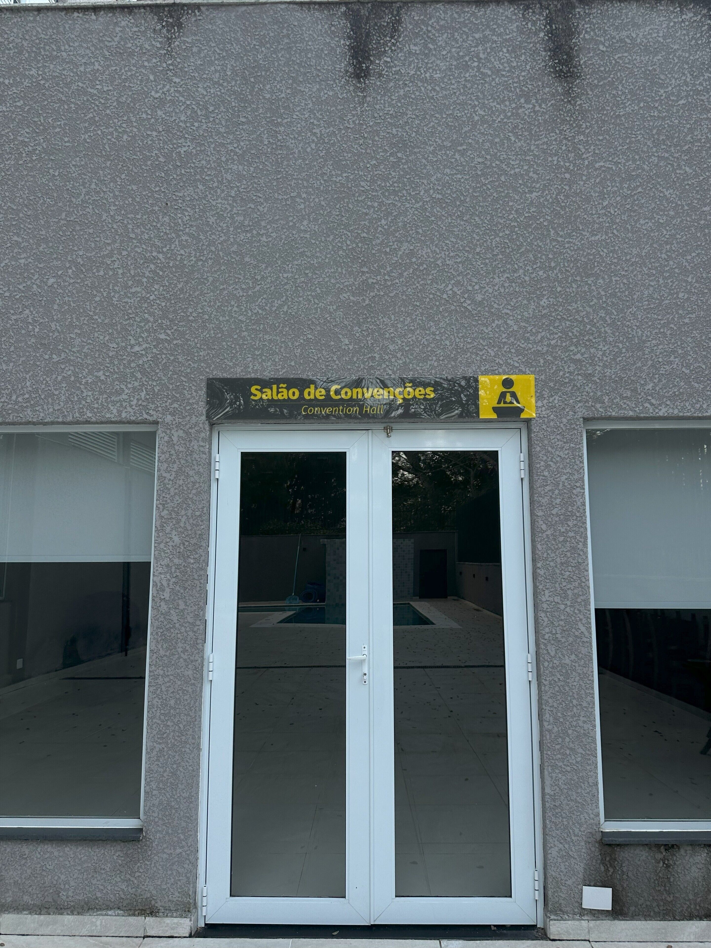 Ein Gebäudeeingang mit einem Schild, auf dem 'Salão de Convencções' steht, und dem Rollstuhlgerechtheitssymbol.
