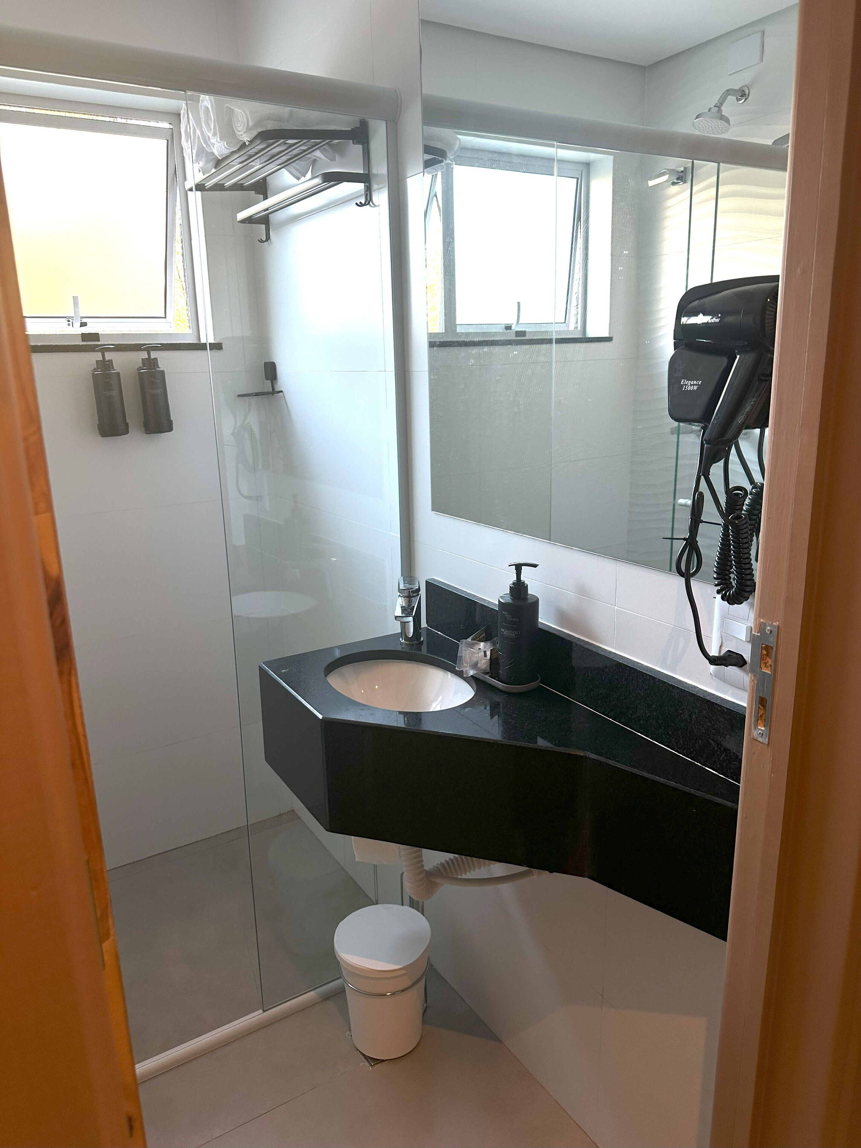 A bathroom with a black sink, white toilet, and a glass shower enclosure.