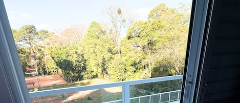 A balcony with a view of a green landscape and trees.