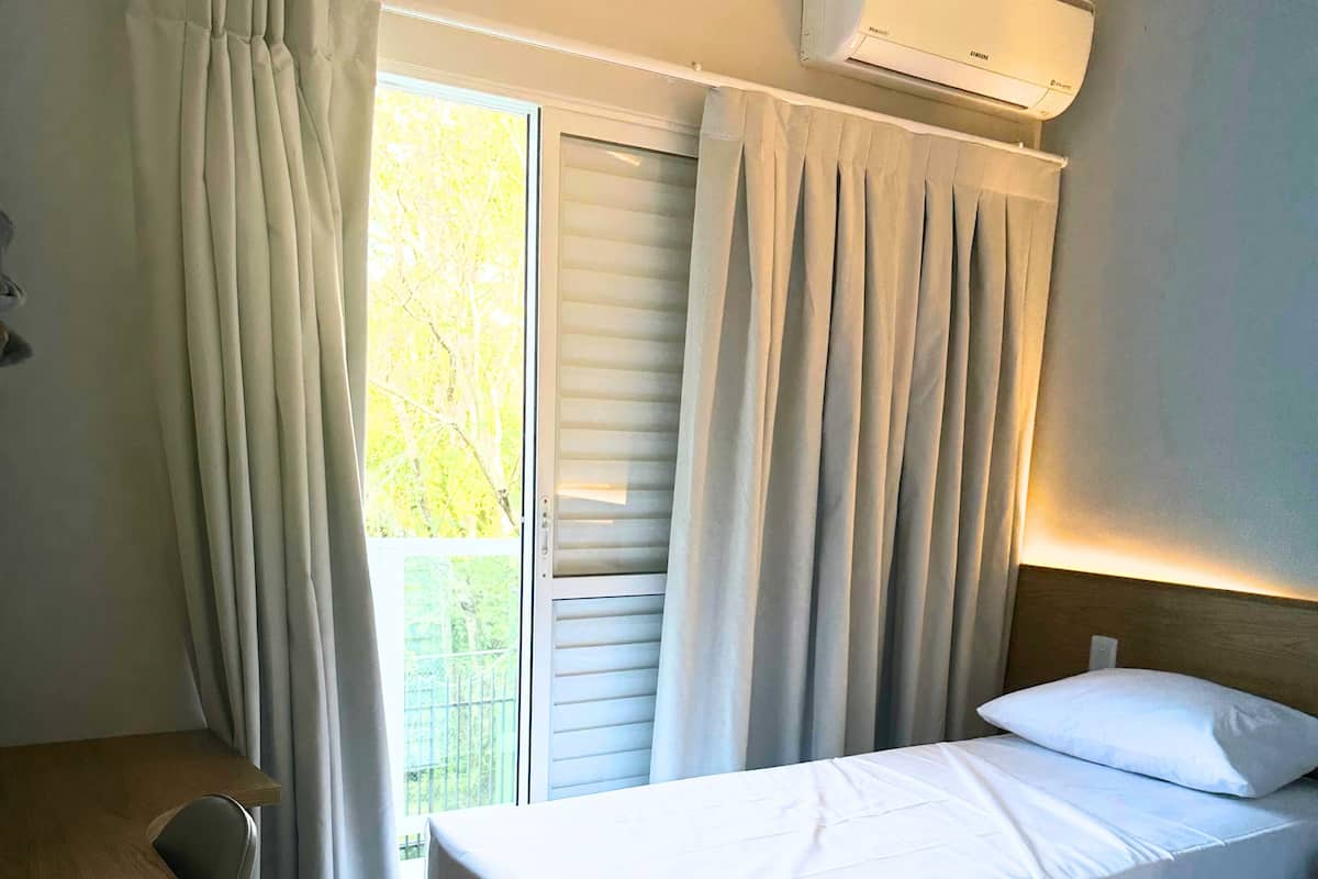 Quarto de hotel com cama, escrivaninha e ar condicionado.
