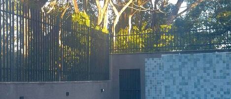 A swimming pool with a tiled edge, surrounded by a low wall and a fence.