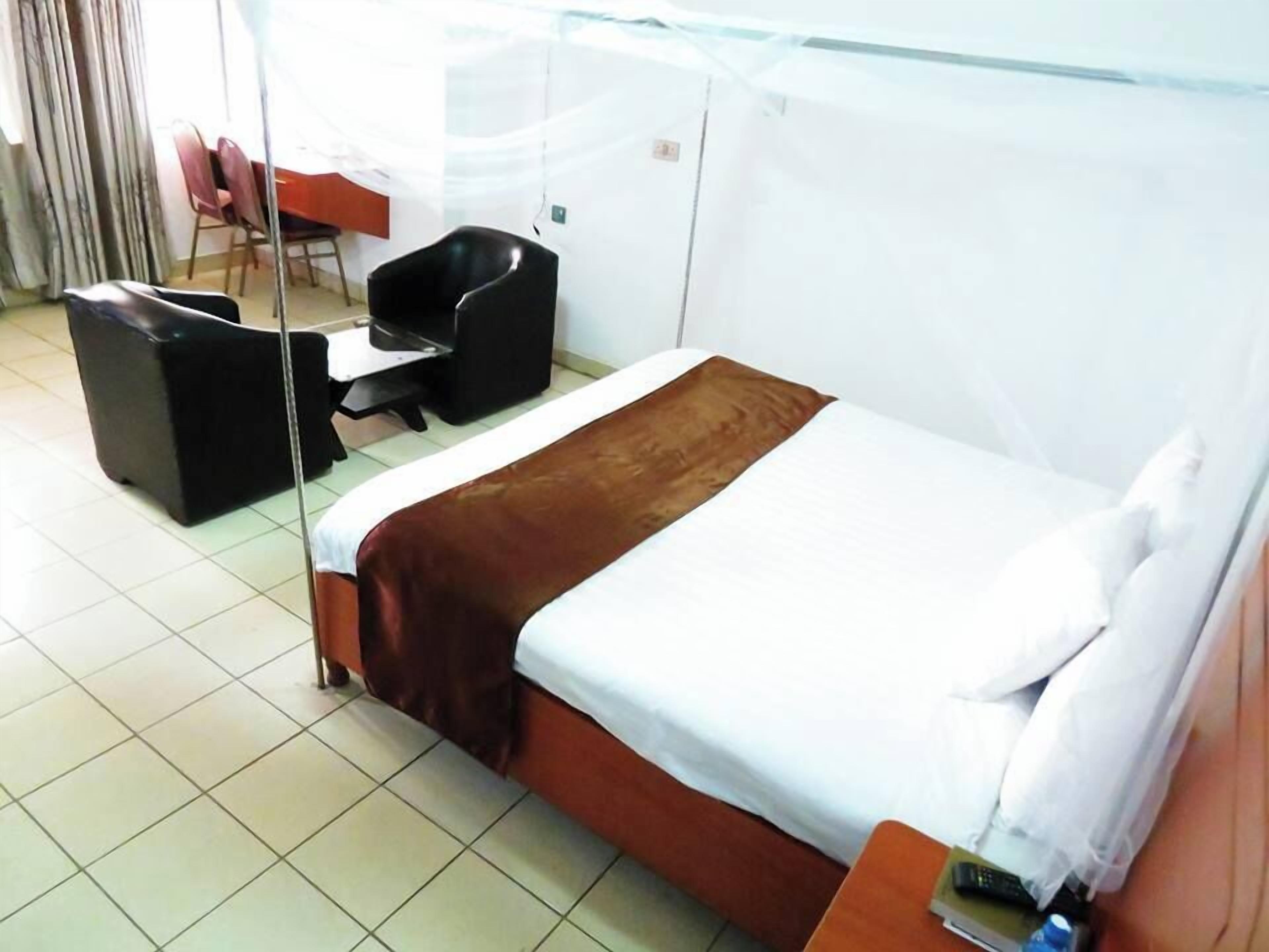 Ein Hotelzimmer mit Bett, Schreibtisch, Stuhl und einem Fenster mit Vorhängen.