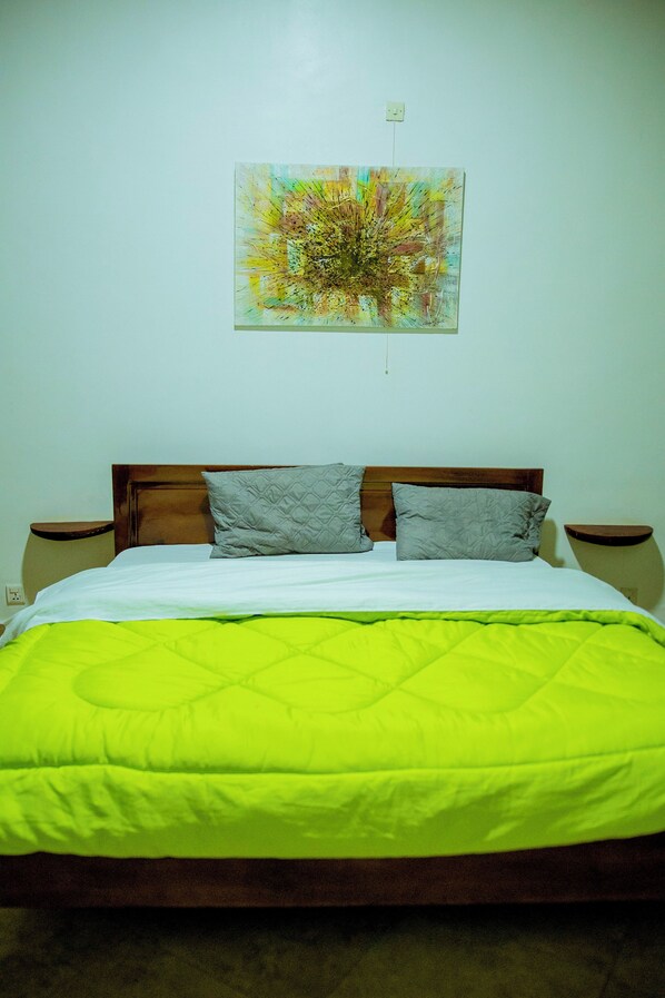 A bed with a wooden headboard, two gray pillows, and a green quilt. - Uzeema Retreat: Great for Big Families! Save More in Kigal (Kigali)