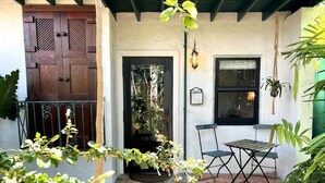 A patio area with a wooden door, a window, a table, and chairs.
