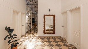 A hallway with a checkered floor, a large mirror, and a potted plant. - Hacienda Oro Verde (San Jerónimo)